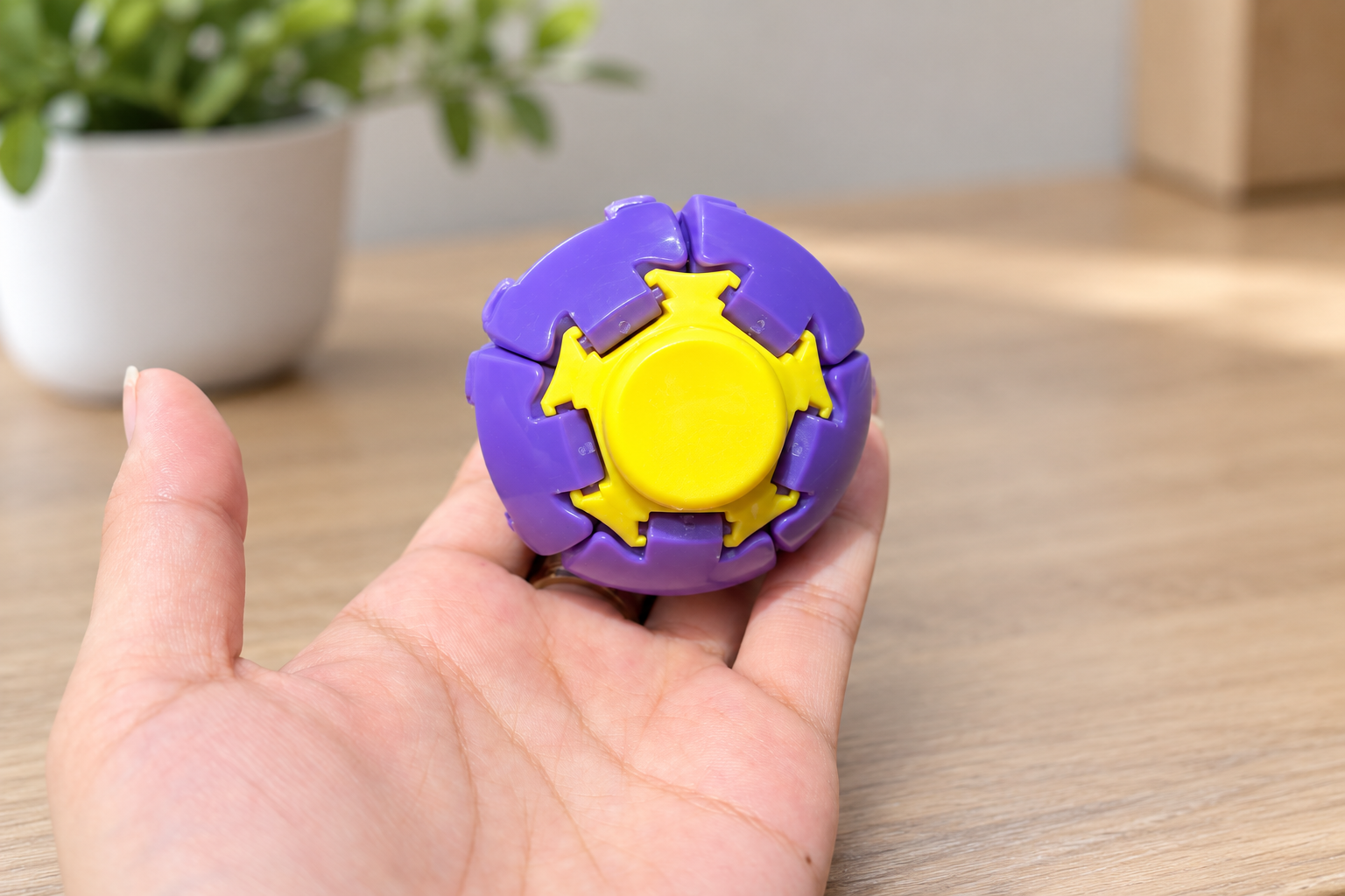 Hand holding a purple and yellow branded fidget toy with moving parts